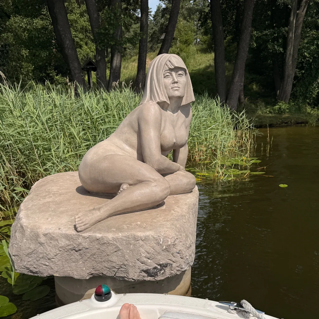 Sandstone sculpture of a seated woman on a boulder by the Rospuda near Augustów
